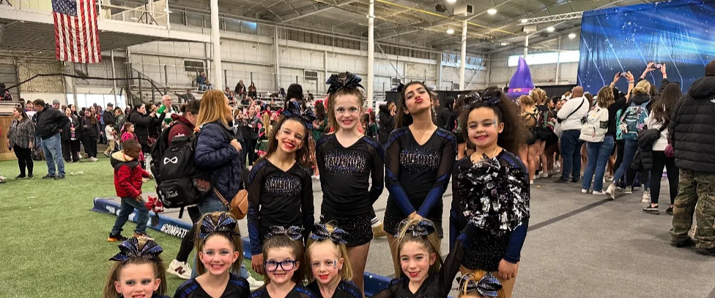 Group of 11 cheerleaders holding up their flag posing for a group picture