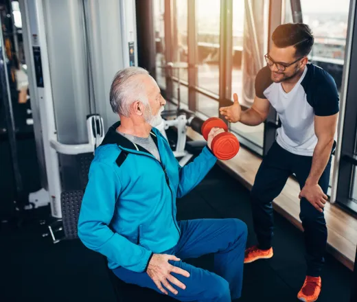 Man exercising in gym with his personal trainer