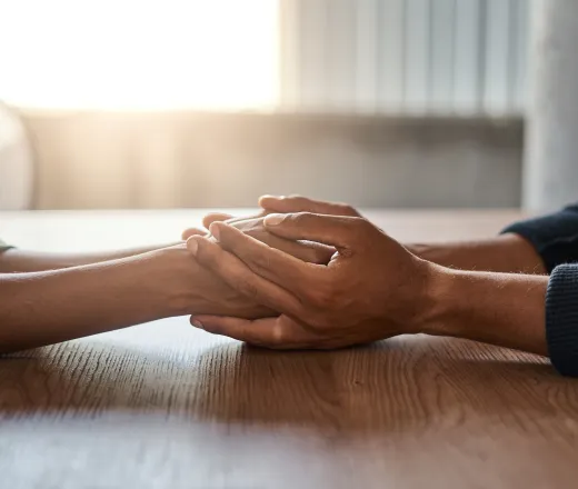 Friends holding each other's hand on desk