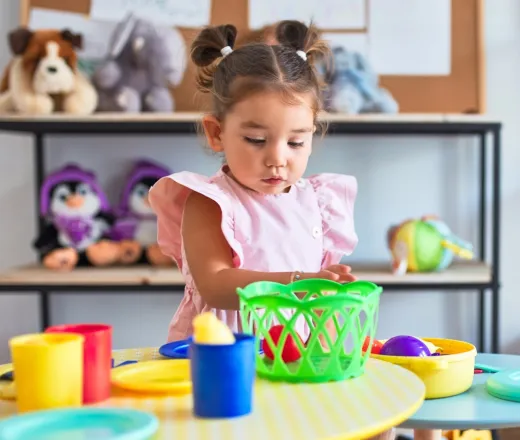 Young beautiful toddler playing with cutlery and food toys on the table