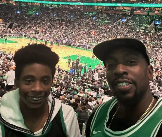 Kid smiling with their mentor at a Celtics game - Mentoring
